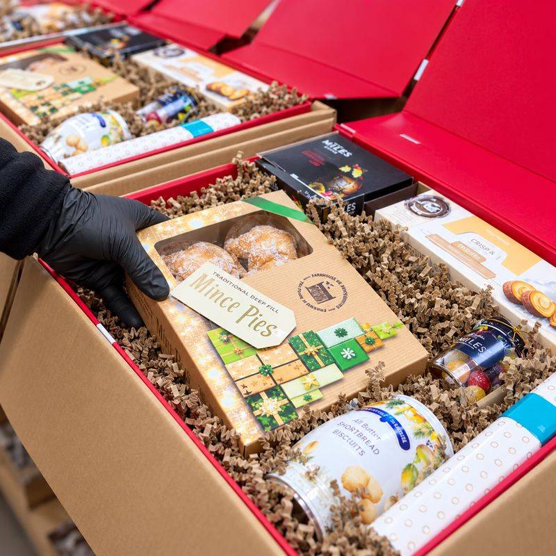 A gifts.ie team member packing mince pies into red Christmas hamper boxes in our Dublin warehouse